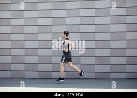 Sportler und Joggen am Morgen. Muskulösen Kerl in Sportbekleidung und Fitness-Tracker, läuft Stockfoto