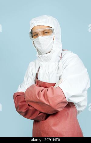 Chirurg in weißem Kostüm auf der ganzen Haut, trägt rote Schürze und Ärmel Stockfoto