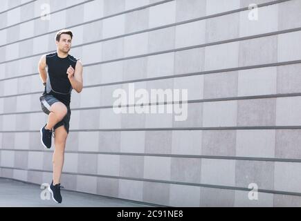 Joggen auf der Straße. Junger Mann in Sportbekleidung und Turnschuhen springt und läuft Stockfoto