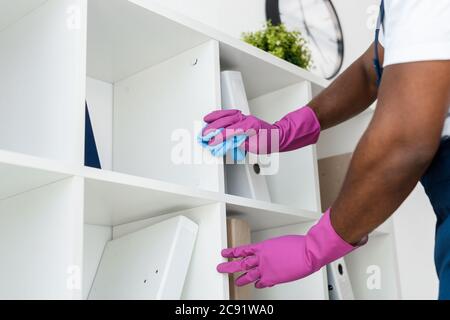 Beschnittene Ansicht der afroamerikanischen Reiniger in Gummihandschuhen und einheitliche Reinigung Schrank im Büro Stockfoto