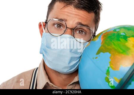 Selektiver Fokus von Nerd in medizinische Maske hält Globus und Blick auf Kamera isoliert auf weiß Stockfoto