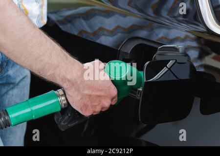 Beschnittene Ansicht des Mannes, der die Düse hält, während er das Auto im Freien betankt Stockfoto