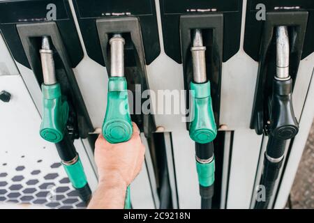 Beschnittene Ansicht des Mannes, der die Zapfpistole an der Tankstelle hält Stockfoto