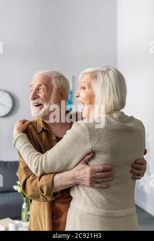 Glückliches Seniorenpaar tanzt, lacht und schaut weg nach Hause Stockfoto