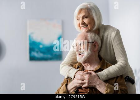 Fröhliche ältere Frau umarmt glücklich behinderten Mann Stockfoto