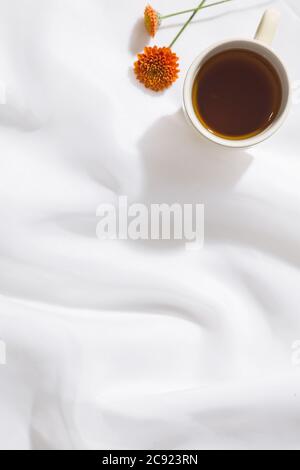 Draufsicht auf Voile Stoff Hintergrund mit einer Tasse Tee, eine orange Blume und Platz für Text Stockfoto