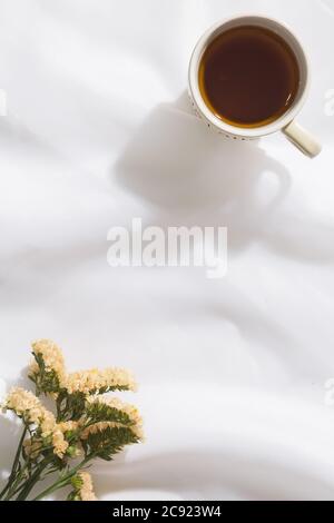 Draufsicht auf Voile Stoff Hintergrund mit einer Tasse Tee und Blumen mit Platz für Text Stockfoto