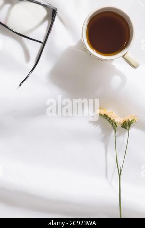 Draufsicht auf Voile Stoff Hintergrund mit einer Tasse Tee, Gläser und Blumen mit Platz für Text Stockfoto