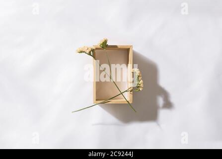 Draufsicht auf eine hölzerne Nische im Voile Stoff Hintergrund mit zwei Blumen, mit Platz für Text Stockfoto