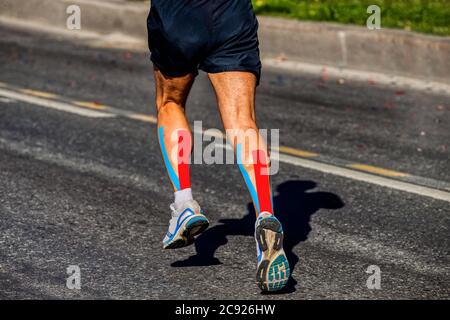 kinesio tapipng auf Wadenmuskel des Athleten Läufer läuft auf dunklem Asphalt Stockfoto