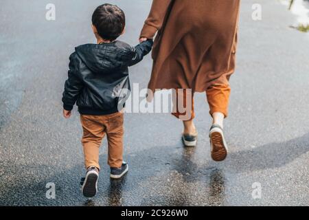 Beschnittene Ansicht der Frau, die Hände hält und mit dem Sohn geht Stockfoto