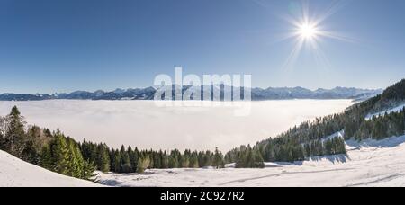 Fantastischer Panoramablick auf Schneeberge mit blauem Himmel und Sonne. Tolles Panorama auf die Bergkette oberhalb der Inversionstal Nebelschicht. Ofterschwanger Stockfoto