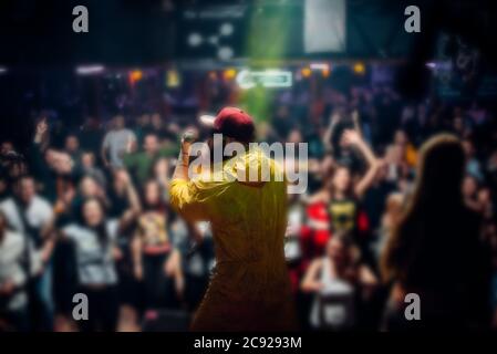 Nahaufnahme eines jungen männlichen Sängers mit Mikrofon. Neonlicht. Stockfoto