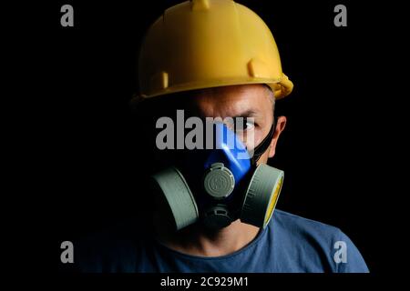 Bergmann in gelb Helm und Atemschutzmaske auf schwarzem Hintergrund.Kohle Industrie, Sicherheit und Schutz Stockfoto