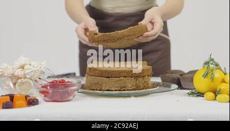 Schritt für Schritt. Mädchen Montage einer Schokoladenkuchen mit hellen bunten Buttercreme Zuckerguss Stockfoto