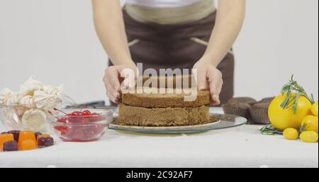 Schritt für Schritt. Mädchen Montage einer Schokoladenkuchen mit hellen bunten Buttercreme Zuckerguss Stockfoto