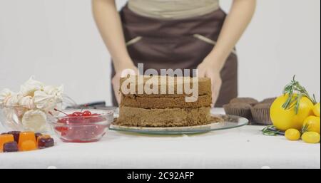 Schritt für Schritt. Mädchen Montage einer Schokoladenkuchen mit hellen bunten Buttercreme Zuckerguss Stockfoto