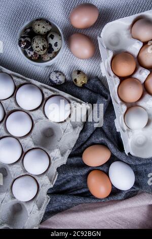 Einige gesunde einheimische Eier und Wachteleier befinden sich in einem Holzkorb neben einem Holzlöffel. Stockfoto