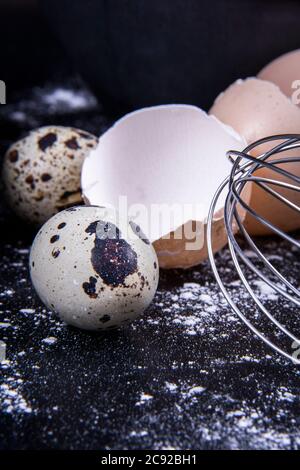 Das Wachtelei befindet sich neben den einheimischen Eiern und einem Eigelb außerhalb oder innerhalb des Tellers. Stockfoto