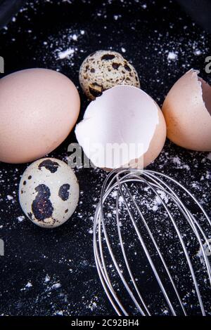 Das Wachtelei befindet sich neben den einheimischen Eiern und einem Eigelb außerhalb oder innerhalb des Tellers. Stockfoto