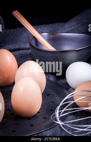 Einheimische Eier neben einer Schüssel oder auf einem weißen Tuch neben einem Handmixer. Stockfoto