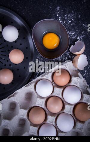 Bild von Eigelb in einer Schüssel neben gesunden Eiern in einem Teller oder weißen Tuch und Küchenutensilien. Stockfoto