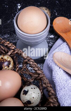 Einige gesunde einheimische Eier und Wachteleier befinden sich in einem Holzkorb neben einem Holzlöffel. Stockfoto