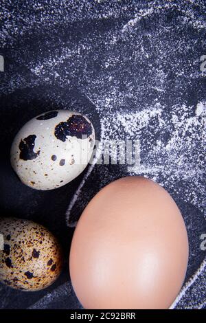 Einige gesunde einheimische Eier und Wachteleier befinden sich in einem Holzkorb neben einem Holzlöffel. Stockfoto