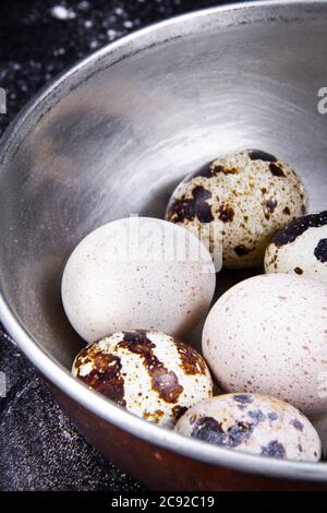 Einige gesunde einheimische Eier und Wachteleier befinden sich in einem Holzkorb neben einem Holzlöffel. Stockfoto