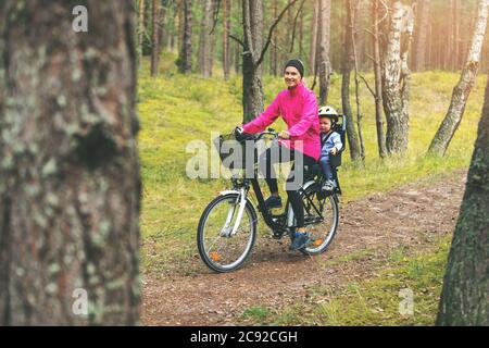 Mutter mit Sohn im Fahrrad Kindersitz Radfahren auf Waldweg Stockfoto