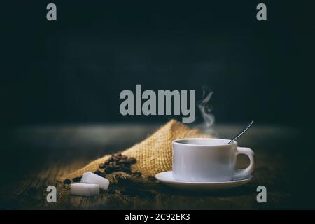 Kaffeebohnen mit weißer Tasse, schwarzer Hintergrund Stockfoto