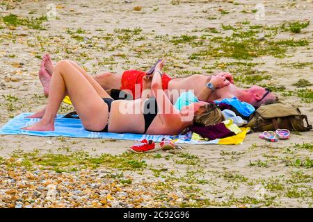 Lyme Regis, Dorset, Großbritannien. Juli 2020. Wetter in Großbritannien. Zwei Paar Sonnenbaden am Strand im Badeort Lyme Regis in Dorset an einem Tag der heißen Sonneneinbete. Bildquelle: Graham Hunt/Alamy Live News Stockfoto