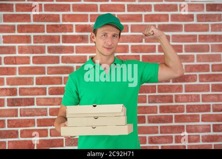 Delivery Mann Mitarbeiter in grünen Kappe T-Shirt bereit, Lieferung Lebensmittel-Box vor dem kundenspezifischen Büro zu senden. Lieferung und Einkauf online Konzept. Stockfoto