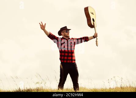 Inspiriert land Musiker. Landhausstil. Sommer Urlaub. Wandern Song. United mit der Natur. Stattlicher Mann mit Gitarre. Country Music Konzept. Gitarrist Land Sänger stand im Feld Himmel Hintergrund. Stockfoto