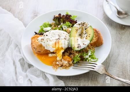 Ein gesunder und ausgewogener Frühstücksteller. Benedict's Egg Spreads auf einem gerösteten Toast mit einer halben Avocado, Quinoa und Salat, gewürzten Gewürzen und Yogu Stockfoto