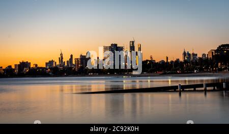 Die Spiegelungen der skyline von melbourne in der Abenddämmerung im stillen Wasser am St kilda Beach Stockfoto