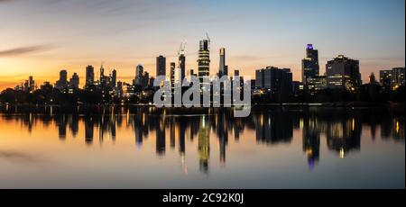 Die Spiegelungen der skyline von melbourne in der Abenddämmerung im stillen Wasser des albert Park Lake Stockfoto