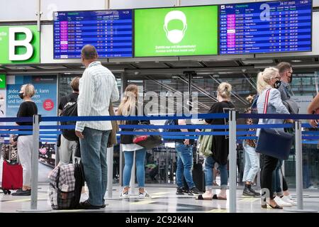 Dortmund, 28. Juli 2020: Passagiere am Flughafen Dortmund tragen vor der Sicherheitskontrolle Mund- und Nasenschutz im Abflugterminal. Die Anzeigetafel zeigt an, dass eine Gesichtsmaske getragen wird. --- Dortmund, 28.07.2020: Flughafen Dortmund, Passagiere tragen Mund-Nasschutz im Terminal Abflug vor dem Security Check. The anzeigetafel while on Gesichtsmaske/Mundschutz hin. Stockfoto