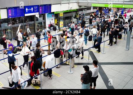 Dortmund, 28. Juli 2020: Passagiere am Flughafen Dortmund tragen vor der Sicherheitskontrolle Mund- und Nasenschutz im Abflugterminal. Die Anzeigetafel zeigt den Sicherheitsabstand an --- Dortmund, 28.07.2020: Dortmund Airport, Passagiere tragen Mund-Nasenschutz im Terminal Abflug vor dem Security Check. Die Anzeigetafel weißt auf Sicherheitsabstand hin. Stockfoto