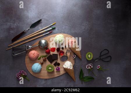Verschiedene Eiswürfel auf einer Farbpalette mit Zutaten in der Mitte einschließlich Erdbeere und Vanille Stockfoto
