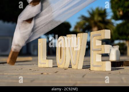 Holzbuchstaben bilden das Wort LIEBE auf dem Boden im Freien bei einer Veranstaltung. Stockfoto