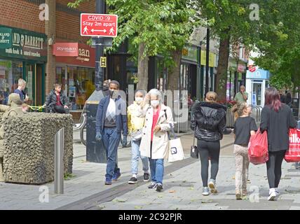 Schwarzes Paar & alte Dame, in Masken in der Fußgängerzone, Beeston. Stockfoto