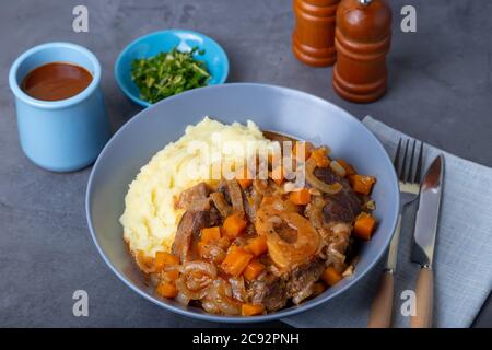 Ossobuco. Kalbsbretter mit Kartoffelpüree, Gremolata und Sauce. Traditionelles italienisches Gericht. Nahaufnahme. Stockfoto