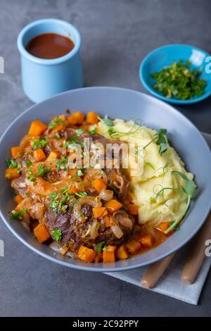 Ossobuco. Kalbsbretter mit Kartoffelpüree, Gremolata und Sauce. Traditionelles italienisches Gericht. Nahaufnahme. Stockfoto