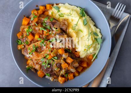 Ossobuco. Kalbsbretter mit Kartoffelpüree, Gremolata und Sauce. Traditionelles italienisches Gericht. Nahaufnahme. Stockfoto