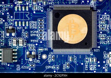 Der Bitcoin liegt auf der cpu, die Goldmünze der Kryptowährung auf dem Mikroprozessor der blauen Leiterplatte ist eine Draufsicht, niemand. Stockfoto