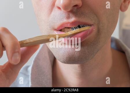 Unkenntlich kaukasischer Mann hält umweltfreundliche Bambuszahnbürste und putzt seine Zähne Stockfoto