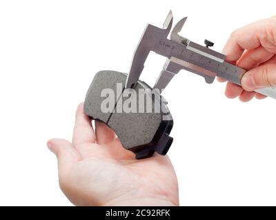 Bremsbeläge des Kfz-Ersatzteiles auf weißem Hintergrund, Messung durch einen Bremssattel der Dicke auf der Hand des Ingenieurs. Stockfoto