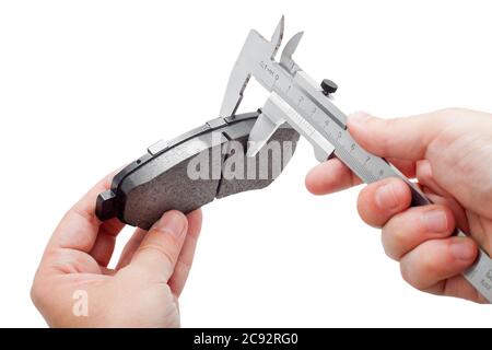 Bremsbeläge des Kfz-Ersatzteiles auf weißem Hintergrund, Messung durch einen Bremssattel der Dicke auf der Hand des Ingenieurs. Stockfoto
