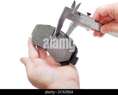 Bremsbeläge des Kfz-Ersatzteiles auf weißem Hintergrund, Messung durch einen Bremssattel der Dicke auf der Hand des Ingenieurs. Stockfoto